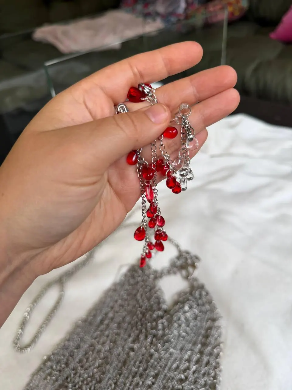 Detachable red glass drop charms held in hand